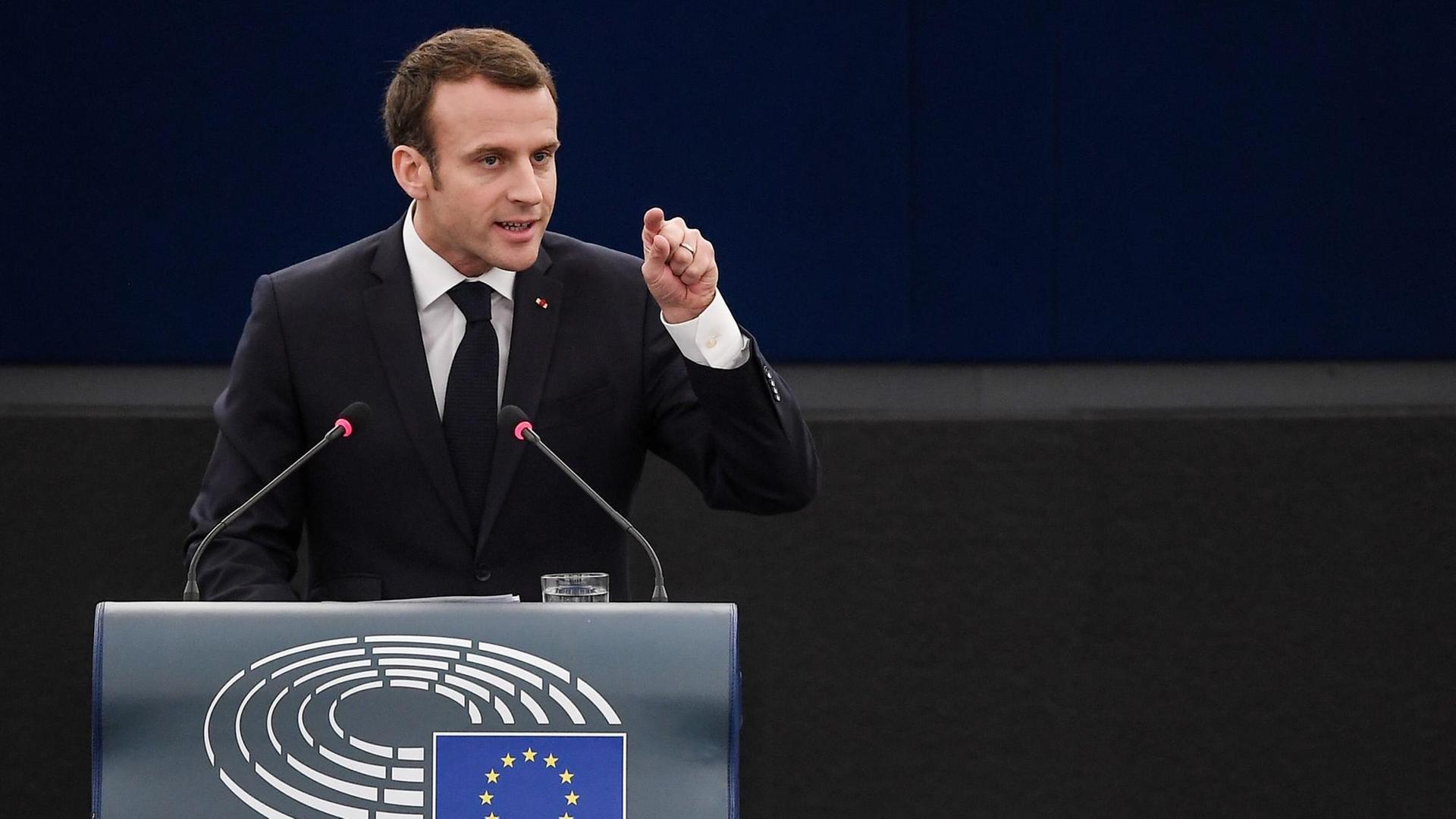 Macron steht am Rednerpult und zeigt mit dem linken Zeigefinger in Richtung der Abgeordneten. Macron steht am Rednerpult und zeigt mit dem linken Zeigefinger in Richtung der Abgeordneten.