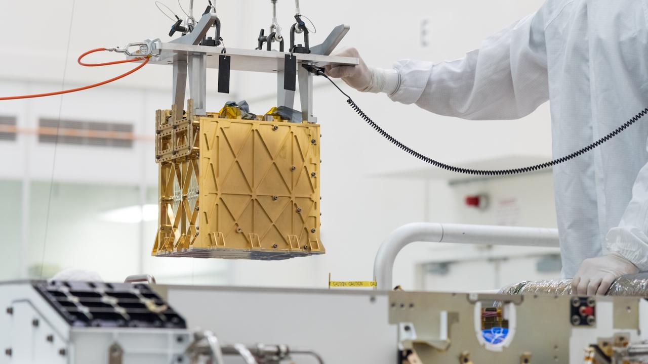 Techniker setzen im Labor den Moxie-Container in den Bauch des Perseverance-Rovers ein.