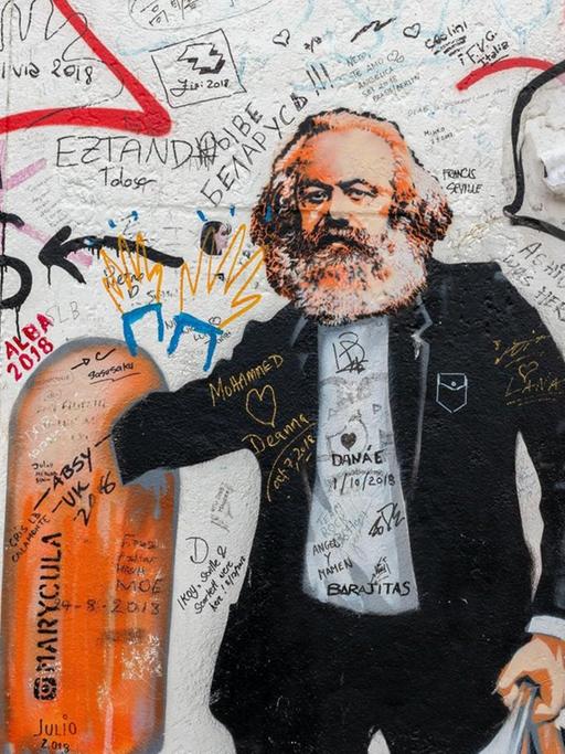 Eine Street-Art-Karikatur an einer Wand zeigt Karl Marx als Flaschensammler, der in einem Mülleimer wühlt.