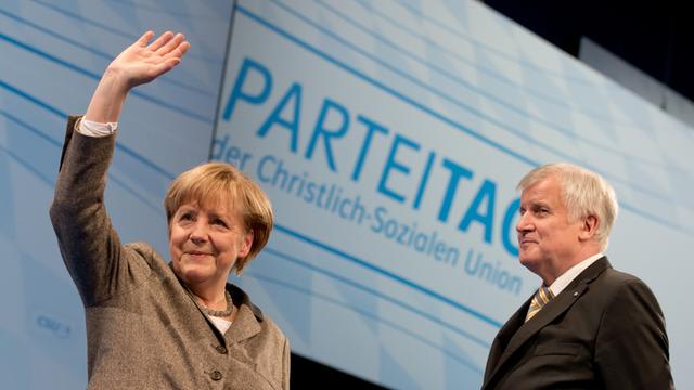 Bundeskanzlerin Angela Merkel winkt in Nürnberg zusammen mit dem bayerischen Ministerpräsident Horst Seehofer beim CSU-Parteitag nach ihrer Rede.