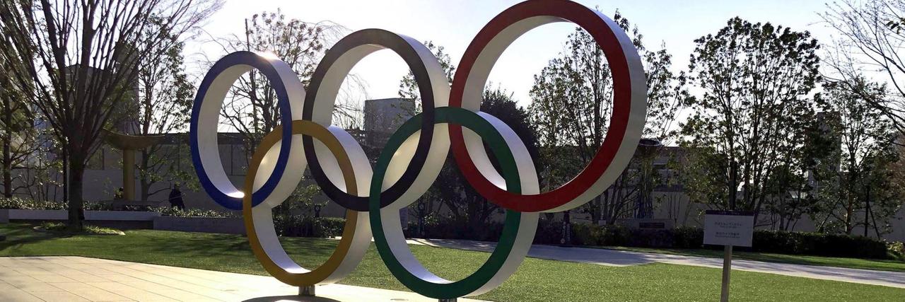 Eine aufgestellte Skulptur der Olympischen Ringe in einer Strasse von Tokio wirft lange Schatten Eine aufgestellte Skulptur der Olympischen Ringe in einer Strasse von Tokio wirft lange Schatten