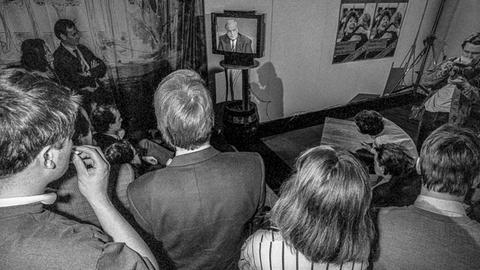 Teilnehmer der Wahlparty der CDU/CSU sehen auf einem Fernsehapparat die Rede von Helmut Kohl.