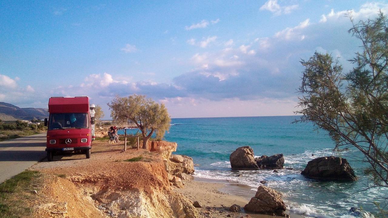 Ein roter Camper-Van steht am Rande einer Straße am Meer. Ein roter Camper-Van steht am Rande einer Straße am Meer.