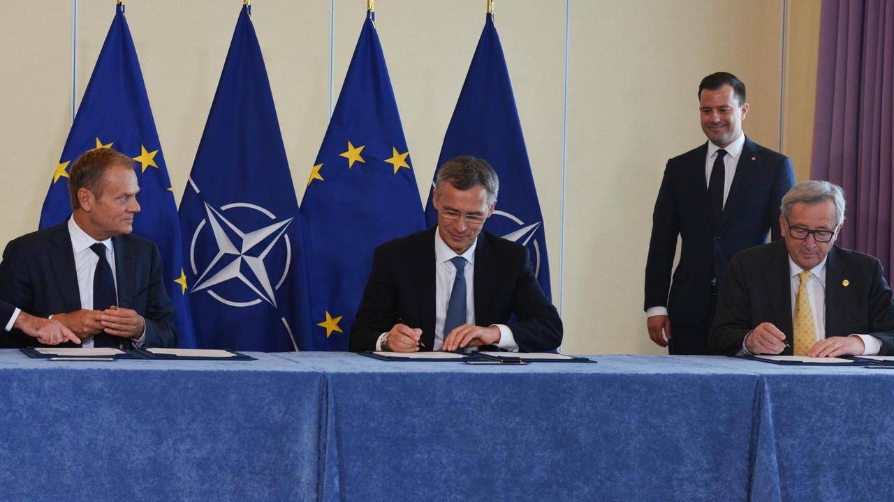 Donald Tusk, Jens Stoltenberg und Jean-Claude Juncker sitzen an einem Tisch nebeneinander und unterzeichnen Dokumente. Donald Tusk, Jens Stoltenberg und Jean-Claude Juncker sitzen an einem Tisch nebeneinander und unterzeichnen Dokumente.