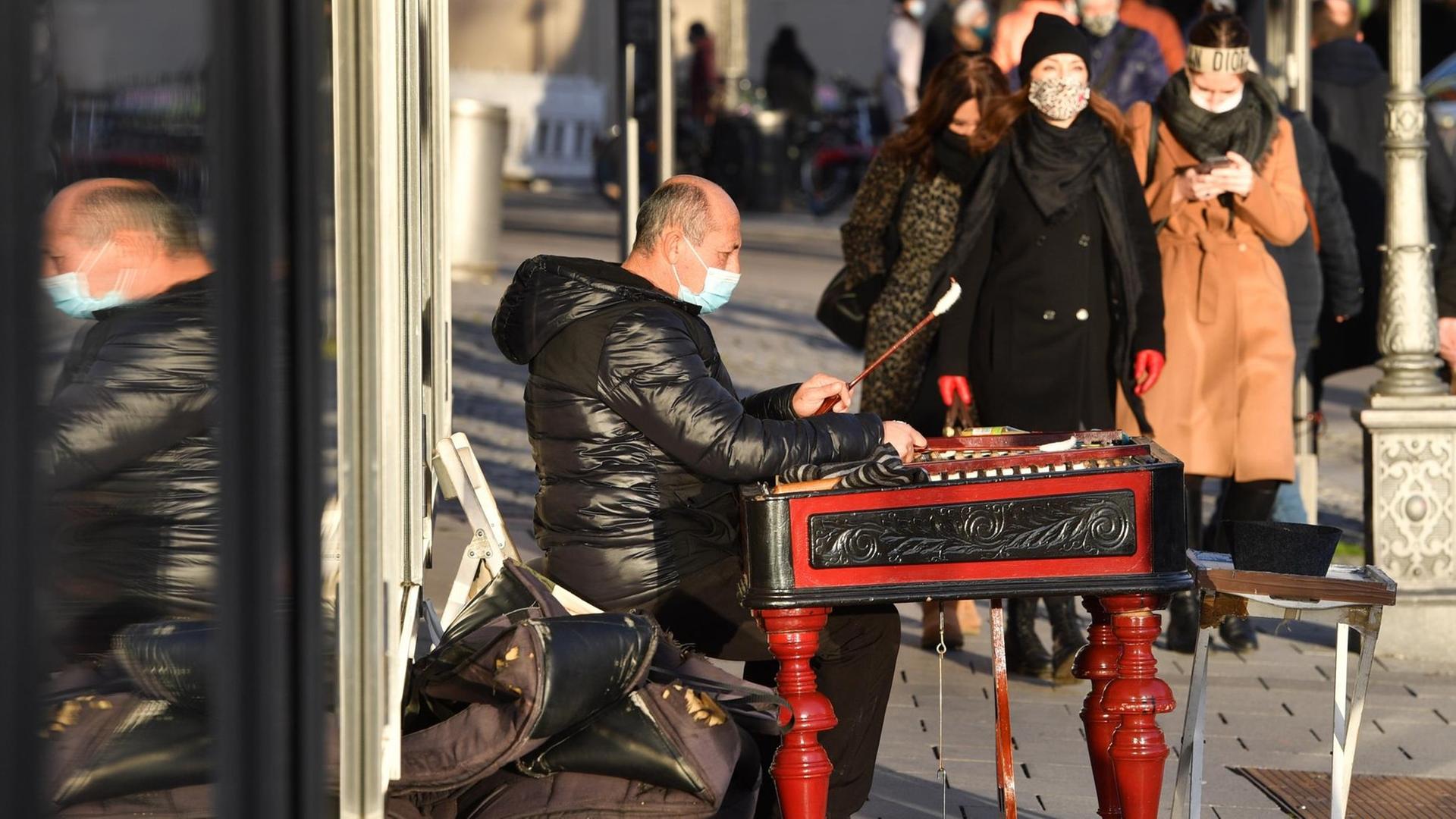 Ein Straßenmusiker trägt Mundschutz, Maske und spielt auf einem Xylophon im Münchner Stadtzentrum. Ein Straßenmusiker trägt Mundschutz, Maske und spielt auf einem Xylophon im Münchner Stadtzentrum.