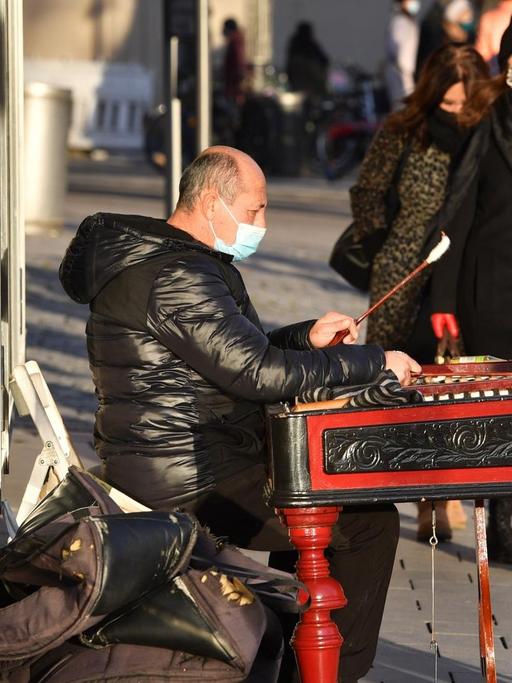 Ein Straßenmusiker trägt Mundschutz, Maske und spielt auf einem Xylophon im Münchner Stadtzentrum.