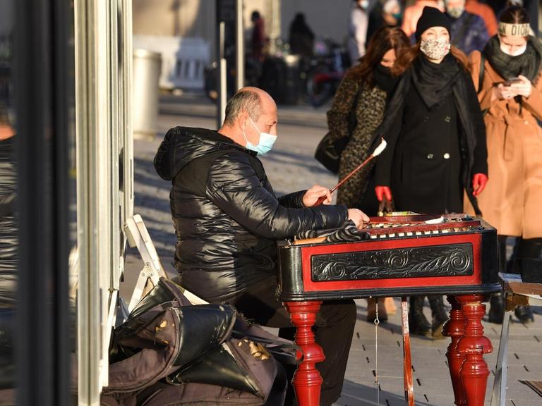 Ein Straßenmusiker trägt Mundschutz, Maske und spielt auf einem Xylophon im Münchner Stadtzentrum.