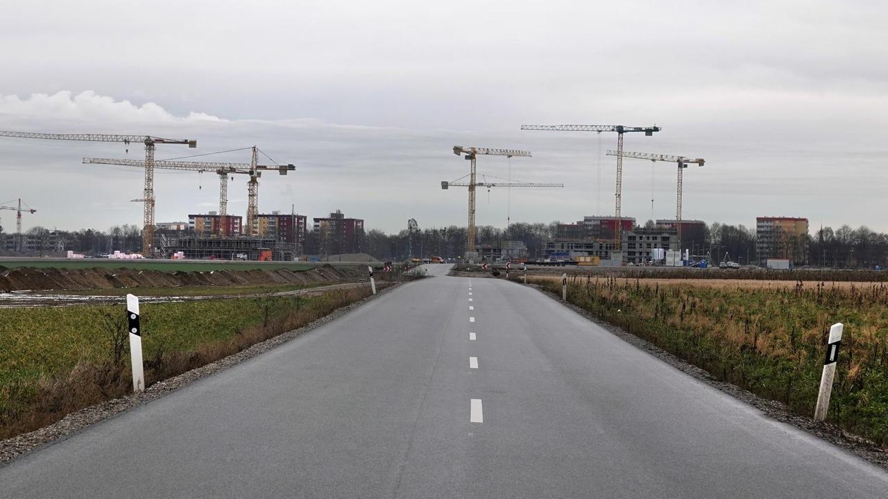  Eine leere Straße führt zu einer Großbaustelle mit vielen Kränen. Im Westen von München entsteht auf rund 350 Hektar der neue Stadtteil Freiham.