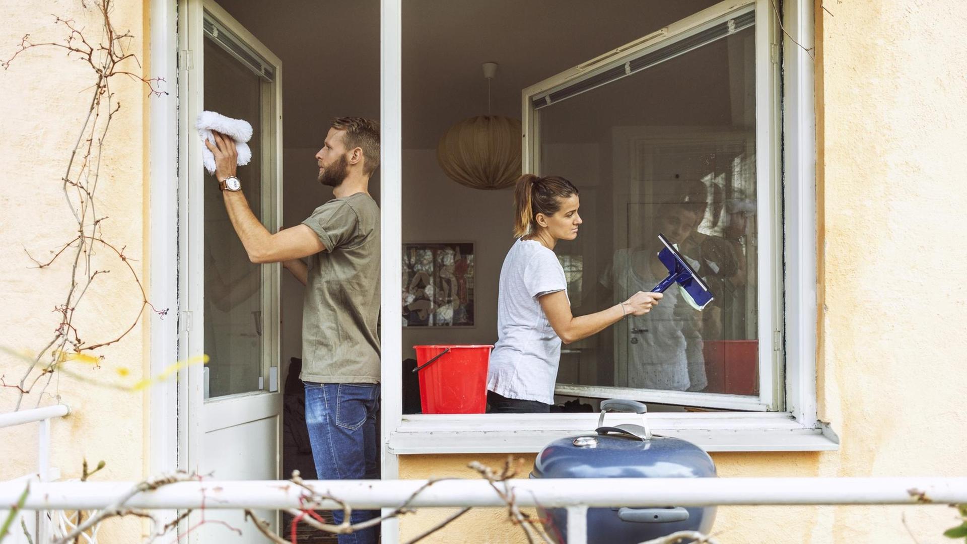 Ein Mann und eine Frau putzen gemeinsam die Fenster. Ein Mann und eine Frau putzen gemeinsam die Fenster.