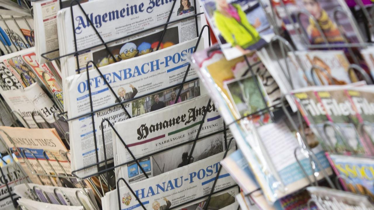 Tageszeitungen stecken an einem Zeitungsstand in Drehständern. Tageszeitungen stecken an einem Zeitungsstand in Drehständern.