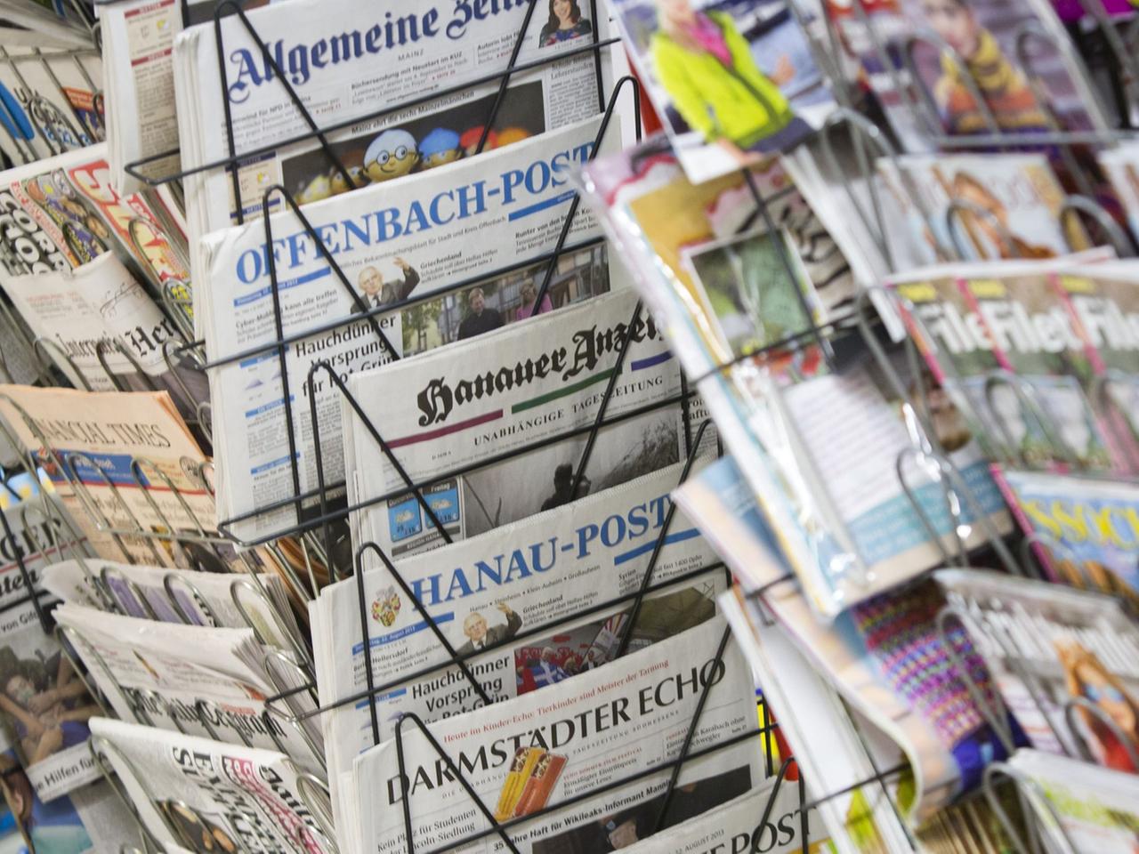 Tageszeitungen stecken an einem Zeitungsstand in Drehständern. Tageszeitungen stecken an einem Zeitungsstand in Drehständern.