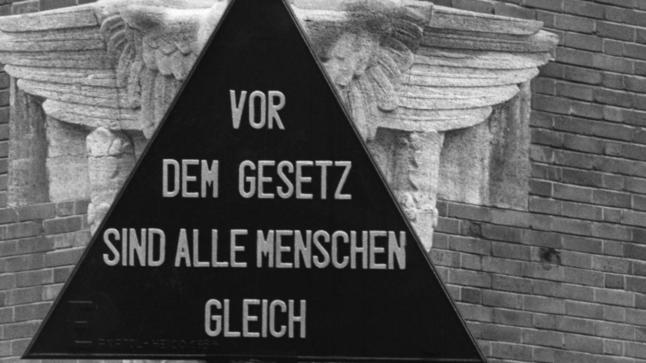 Dieses Symbol für die Gewaltenteilung schmückt das Polizeipräsidium in Düsseldorf, der Text wurde dem Grundgesetz entnommen.