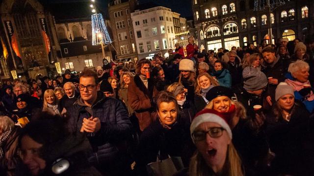 In Amsterdam feiern Menschen jedes Jahr zusammen im Dezember das Lichterspiel am 20 hohen Weihnachtsbaum auf dem Dam, dem zentralen Platz der Stadt vor dem Königspalast.