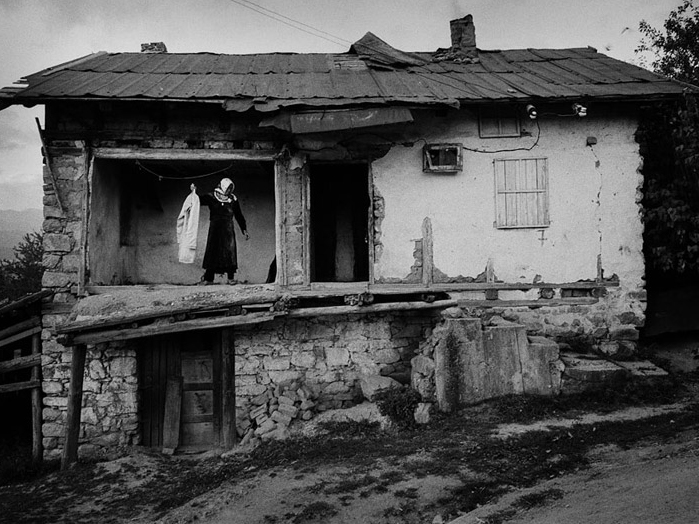 Eine Frau steht im ersten Stock eines halb verfallenen Hauses. Eine Frau steht im ersten Stock eines halb verfallenen Hauses.