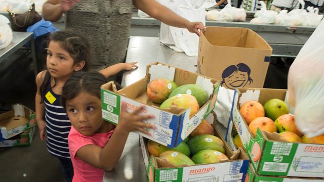 Zwei Kinder und Kisten mit Obst an einer Lebensmittel-Verteilungsstelle in Los Angeles.
