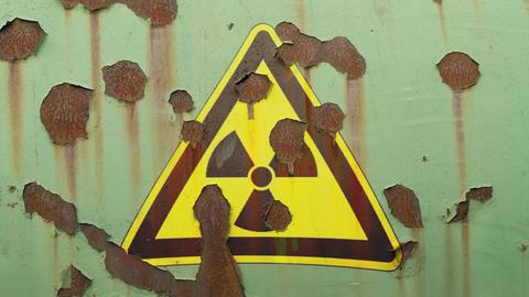 Abblätterndes Hinweisschild auf Radioaktivität an einer Mauer