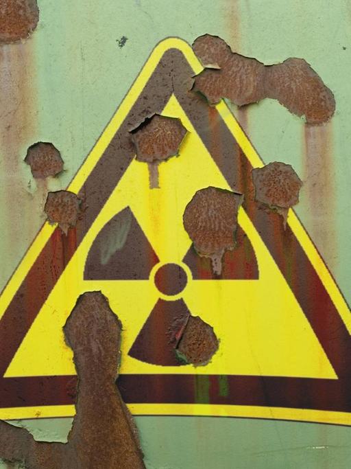 Abblätterndes Hinweisschild auf Radioaktivität an einer Mauer