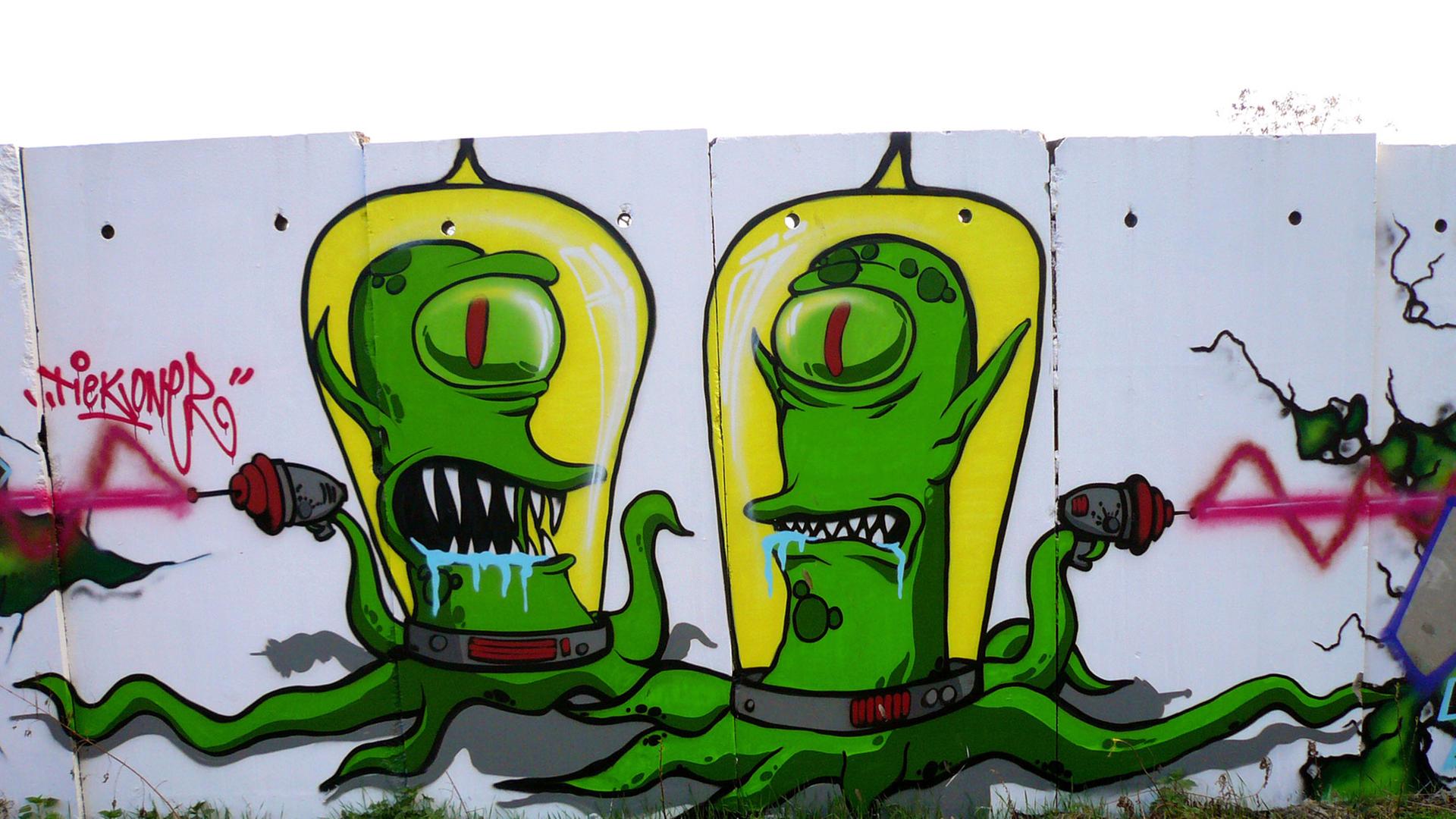 Zwei Außerirdische aus der Comic-Fernsehserie "Die Simpsons" an Mauersegmenten in Berlin.
