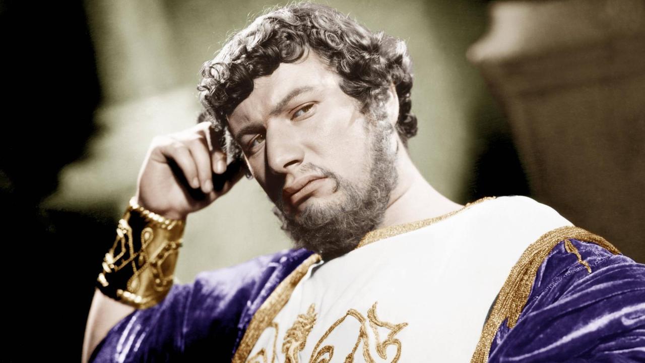 Ein Film-Still zeigt den Schauspieler Peter Ustinov als Kaiser Nero in purpurnem Gold-verzierten Gewand den Kopf nachdenklich auf die rechte Hand gestützt Ein Film-Still zeigt den Schauspieler Peter Ustinov als Kaiser Nero in purpurnem Gold-verzierten Gewand den Kopf nachdenklich auf die rechte Hand gestützt