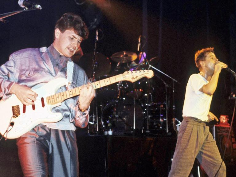 Gitarrist Charlie Burchill und Sänger Jim Kerr von den Simple Minds stehen auf einer Kozertbühne.
