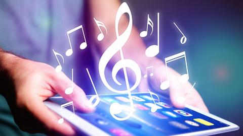 Aus einem Tablet erscheinen musikaliche Zeichen, wie Noten und Notenschlüssel.