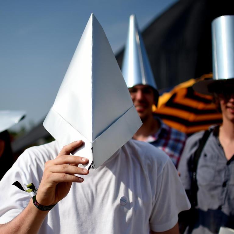 Verschiedene Menschen tragen selbstgebastelte Alu-Hüte
