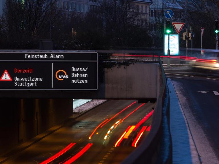 Autos fahren am 18.01.2016 in Stuttgart (Baden-Württemberg) durch die Innenstadt, während auf einer Anzeige ein Feinstaub-Alarm für die Umweltzone Stuttgart angezeigt und auf öffentliche Verkehrsmittel hingewiesen wird.