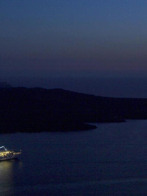 Beleuchtetes Kreuzfahrtschiff in der Nacht.