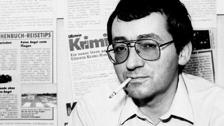 Der Autor Jörg Fauser während der Buchmesse 1985 in Frankfurt / Main mit großer Brille und Zigarette im Mundwinkel auf eine Schwarz-Weiß-Aufnahme. Der Autor Jörg Fauser während der Buchmesse 1985 in Frankfurt / Main mit großer Brille und Zigarette im Mundwinkel auf eine Schwarz-Weiß-Aufnahme.