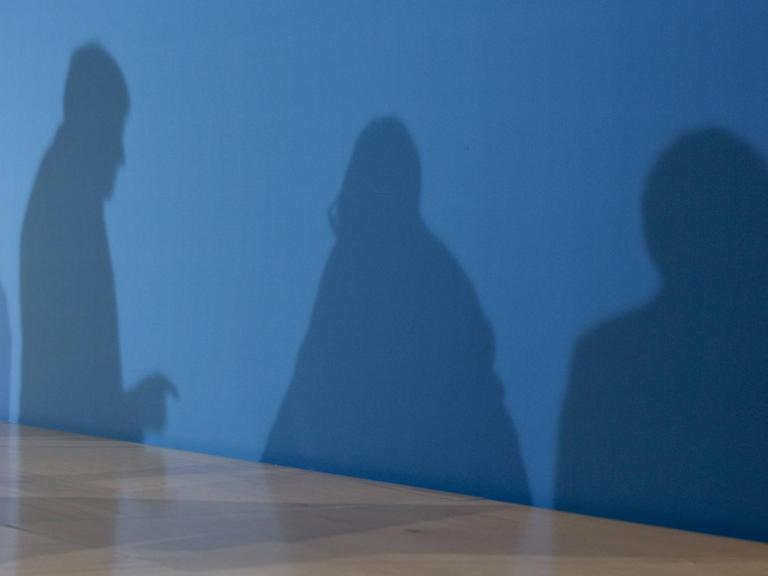 Die Schatten von Horst Seehofer, Angela Merkel und Martin Schulz auf einer blauen Wand