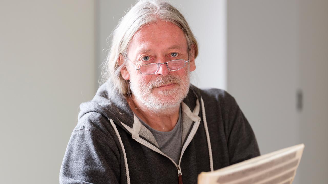 Der Fotograf Harald Hauswald guckt in die Kamera und hält eine Folie mit Negativen in der Hand. Der Fotograf Harald Hauswald guckt in die Kamera und hält eine Folie mit Negativen in der Hand.