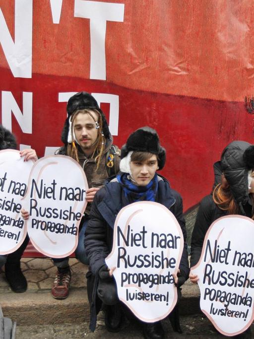 Ukrainische Aktivisten halten vor einem Porträt des niederländischen Malers Vincent van Gogh Plakate in Ohrform hoch mit der Aufschrift "Nicht auf russische Propaganda hören."