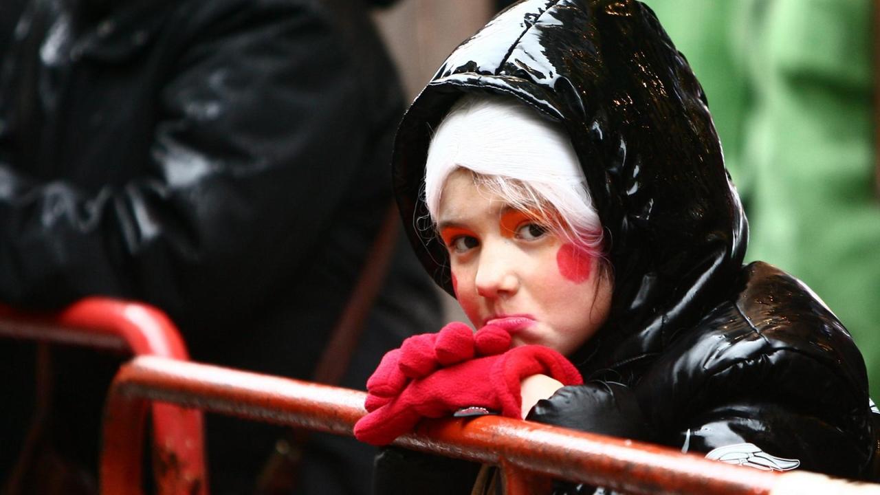 Ein kleines Mädchen zieht eine Schnute, während es im Regen auf den Start des Rosenmontagszuges wartet. Ein kleines Mädchen zieht eine Schnute, während es im Regen auf den Start des Rosenmontagszuges wartet.