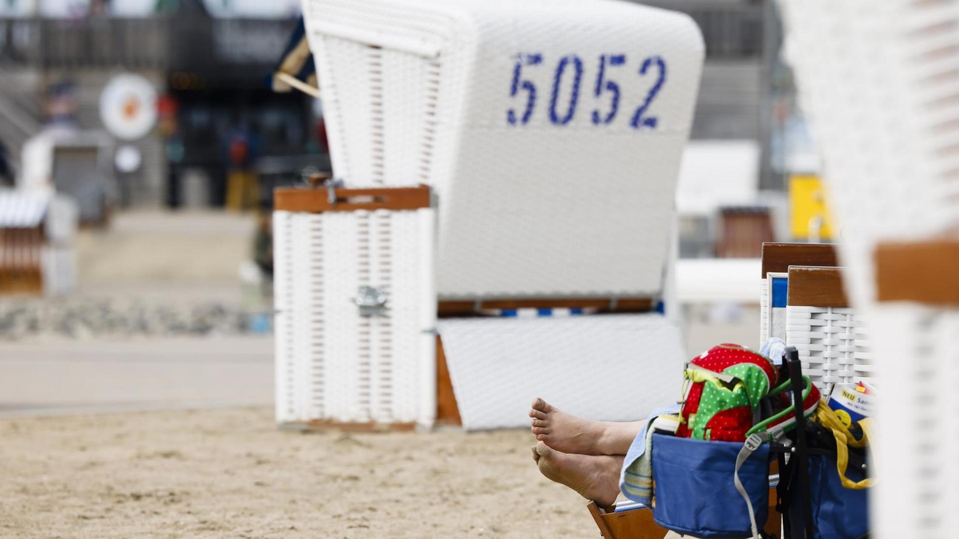 Die Füße einer Urlauberin schauen aus einem Strandkorb heraus. Die Füße einer Urlauberin schauen aus einem Strandkorb heraus.