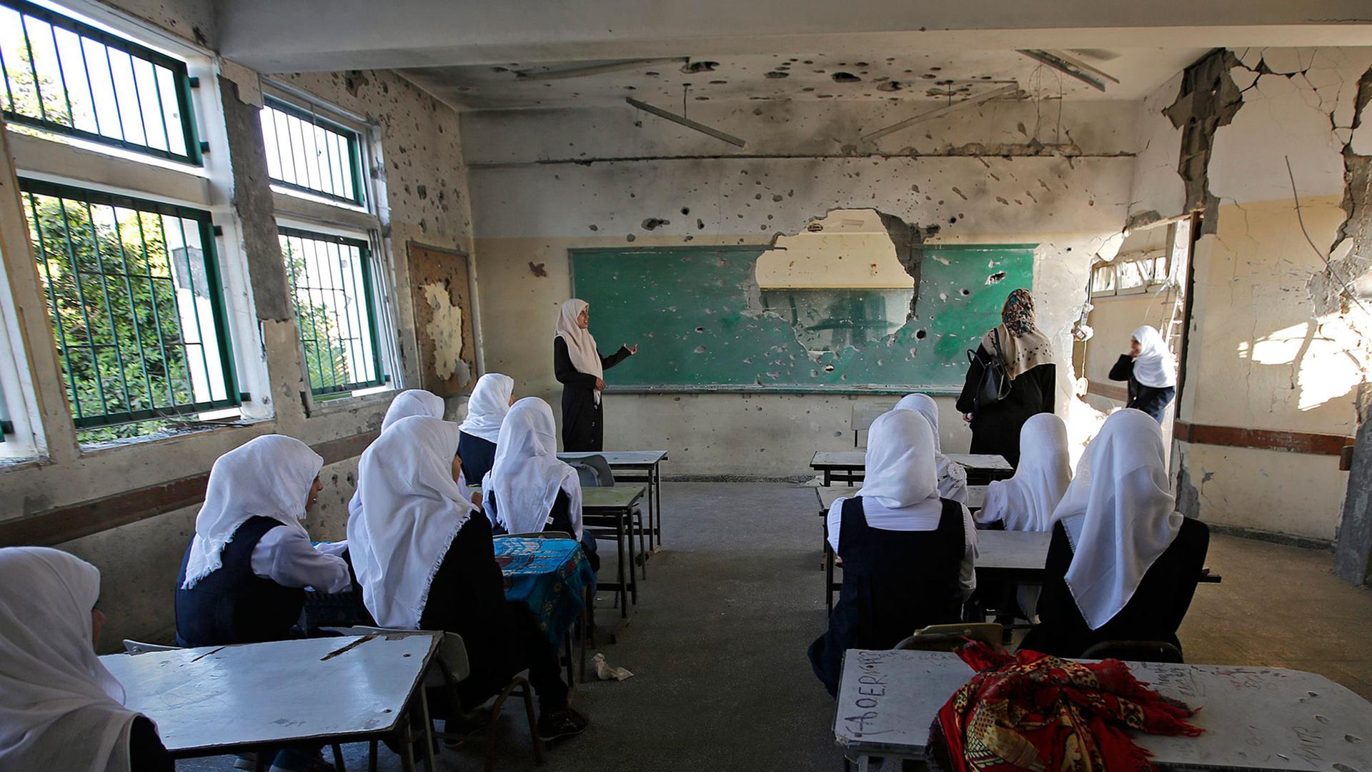 Palästinensische Schülerinnen sitzen am ersten Tag des neuen Schuljahrs in einem zerstörten Klassenzimmer.