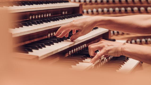 Die Hände von Iveta Apkalna spielen auf verschiedenen Tabulaturen, den übereinander liegenden Tastaturen der Orgel.