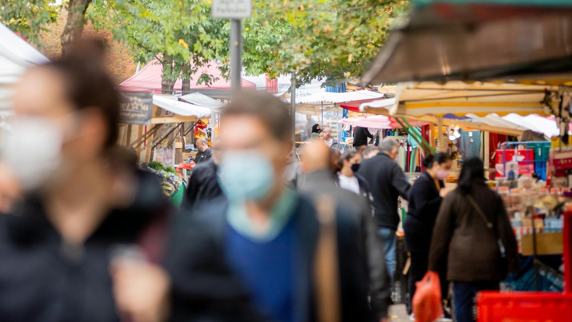 Menschen tragen Mund-Nasen-Bedeckungen und gehen in Berlin-Kreuzberg über den Markt am Maybachufer. Menschen tragen Mund-Nasen-Bedeckungen und gehen in Berlin-Kreuzberg über den Markt am Maybachufer.