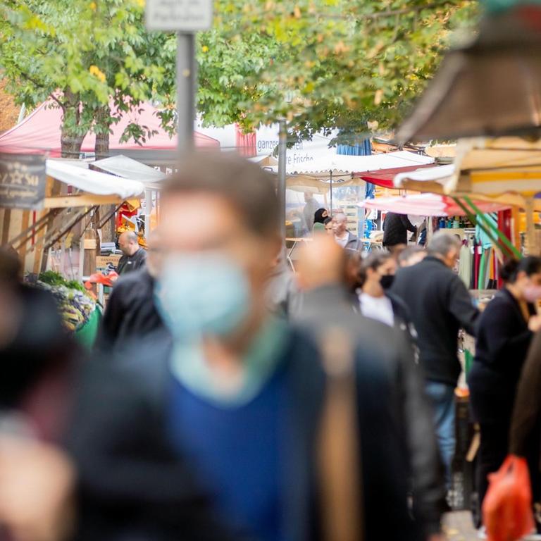 Menschen tragen Mund-Nasen-Bedeckungen und gehen in Berlin-Kreuzberg über den Markt am Maybachufer.