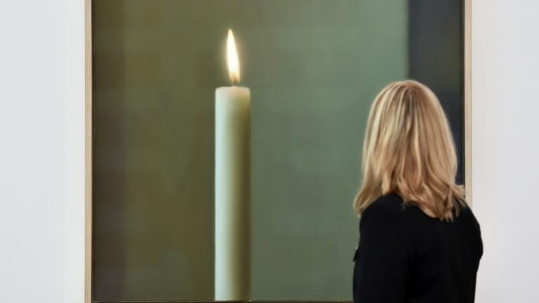 Eine Besucherin der Ausstellung betrachtet Gerhard Richters Werk "Kerze", ein Bild mit einer großen Kerze drauf, Frau ist nur von hinten zu sehen.