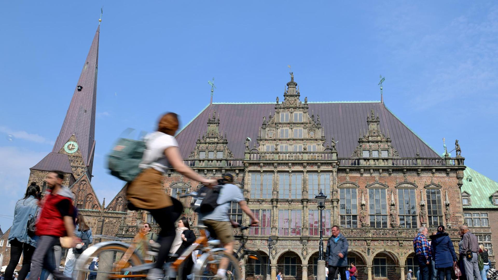 Zwei Radfahrer fahren über den Bremer Marktplatz, im Hintergrund das Rathaus. Zwei Radfahrer fahren über den Bremer Marktplatz, im Hintergrund das Rathaus.