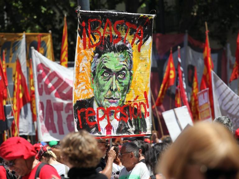 Ein Demonstrant hält in Buenos Aires (Argentinien) bei einem Protest ein Bild von Präsident Macri mit der Aufschrift "Stoppt die Polizei Unterdrückung!" hoch.