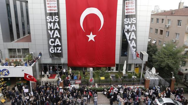 Anhänger der Gülen-Bewergung protestieren am Dienstag vor dem Gebäude der Koza Ipek Mediengruppe in Istanbul, an dem eine riesige türkische Fahne hängt
