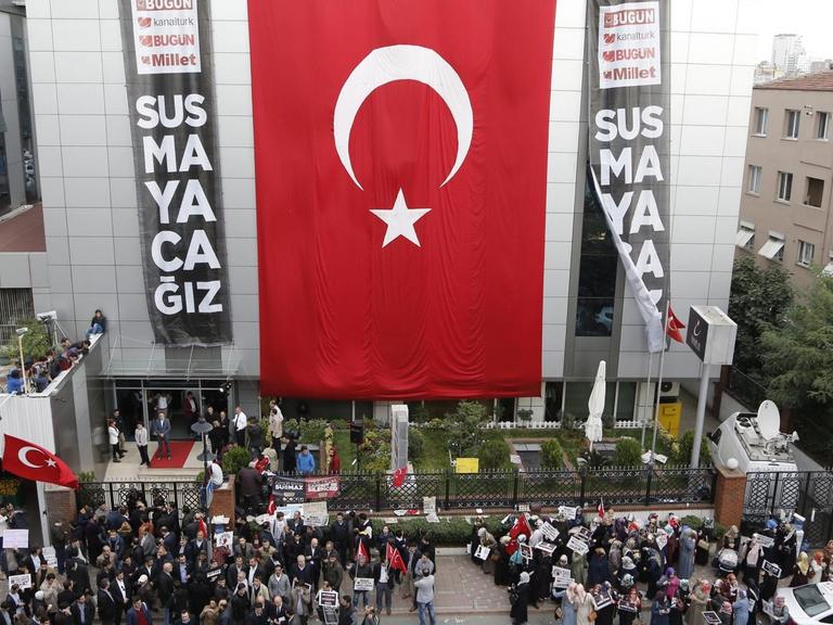 Anhänger der Gülen-Bewergung protestieren am Dienstag vor dem Gebäude der Koza Ipek Mediengruppe in Istanbul, an dem eine riesige türkische Fahne hängt
