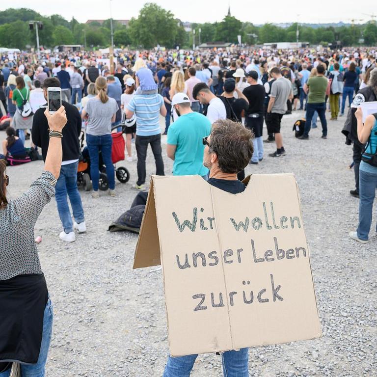 Ein Mann mit einem Schild, auf dem «Wir wollen unser Leben zurück» steht.