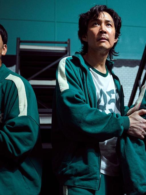 Szene aus dem Überlebenskampfspiel "Squid Game" mit: Lee Jung-jae, Greg Chun, Stephen Fu. Netflix Serie aus Südkorea, 2021.