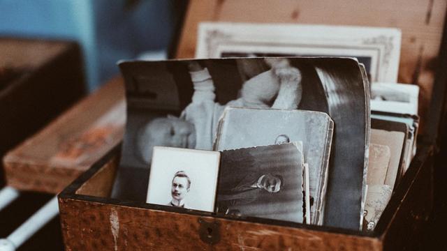 Eine Holzkiste mit vielen, alten Schwarz-Weiß-Fotos.