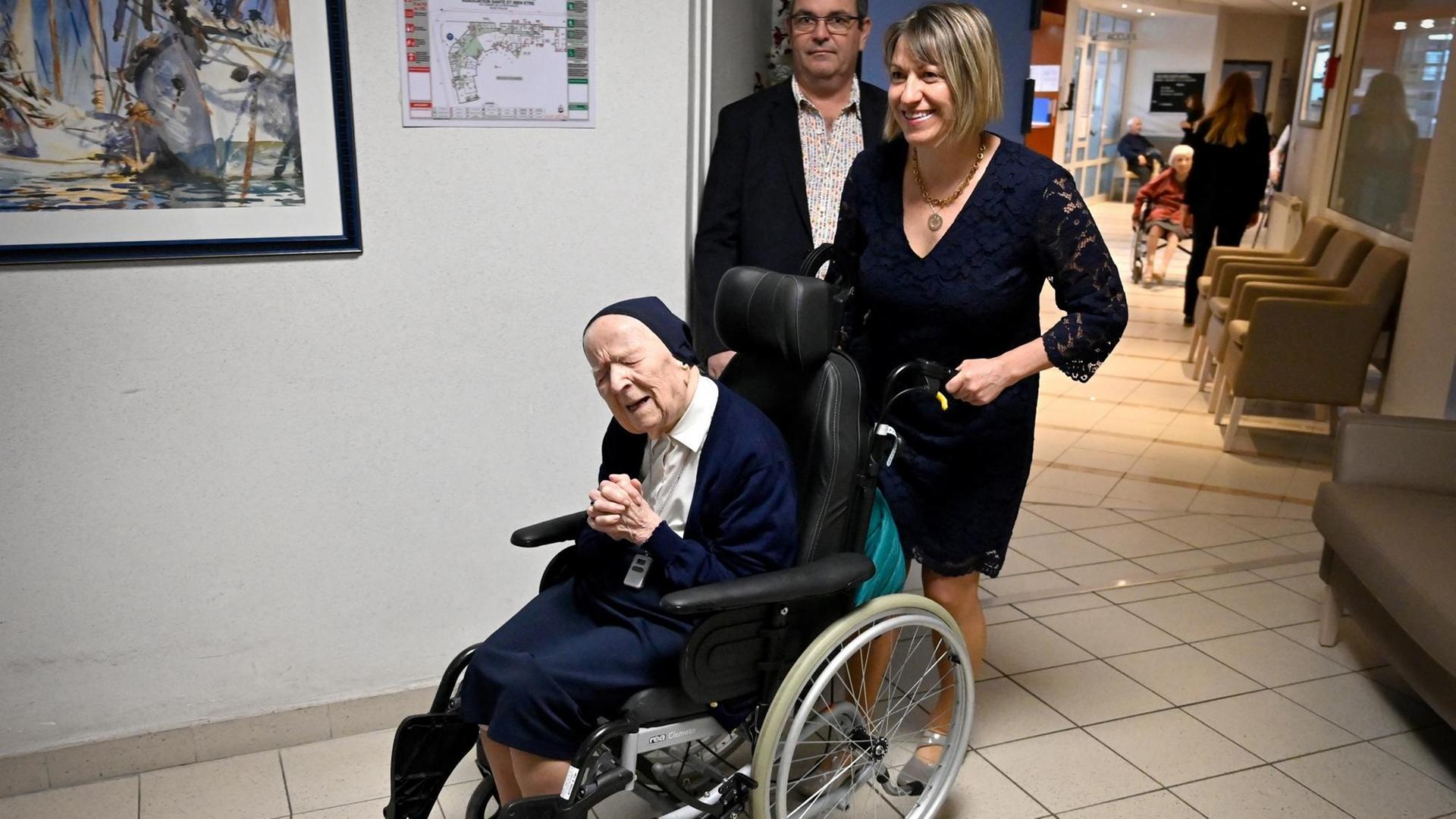 Die alte Frau sitzt in einem Roll-Stuhl und hat die Hände gefaltet. Die alte Frau sitzt in einem Roll-Stuhl und hat die Hände gefaltet.
