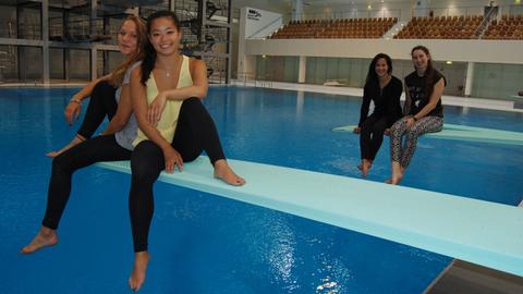 Die Wasserspringerinnen Talisa Lemke, My Phan, Kieu Duong und Anna Spenke (v.lks.) sitzen zu Zweit auf je einem Ein-Meter-Brett in einer Schwimmhalle.