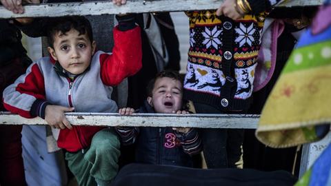 Syrische Flüchtlingskinder warten an der Grenze zur Türkei hinter einem Zaun