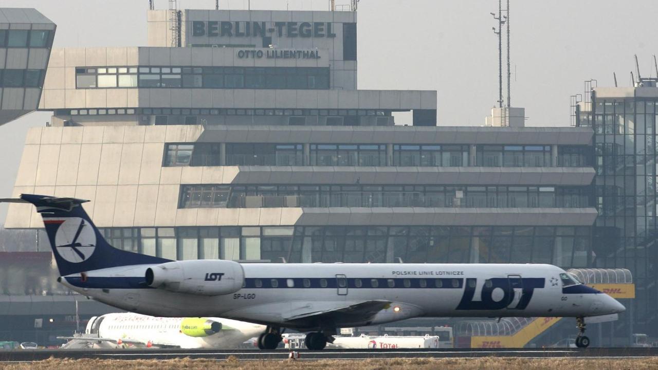 Ein Verkehrsflugzeug der polnischen Fluggesellschaft Lot steht auf dem Flughafen Berlin Tegel. Im Hintergrund sieht man den Tower und das Flughafengebäude. Ein Verkehrsflugzeug der polnischen Fluggesellschaft Lot steht auf dem Flughafen Berlin Tegel. Im Hintergrund sieht man den Tower und das Flughafengebäude.